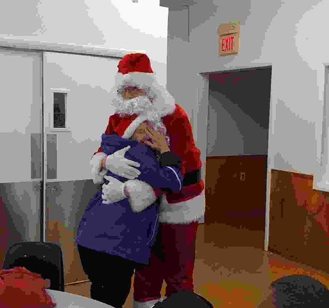 Home for the Holidays photo of Santa hugging female participant