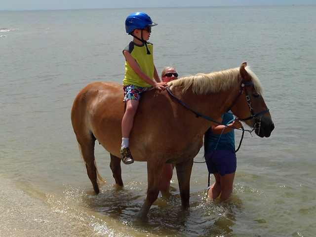 Child riding horseback on the beach.